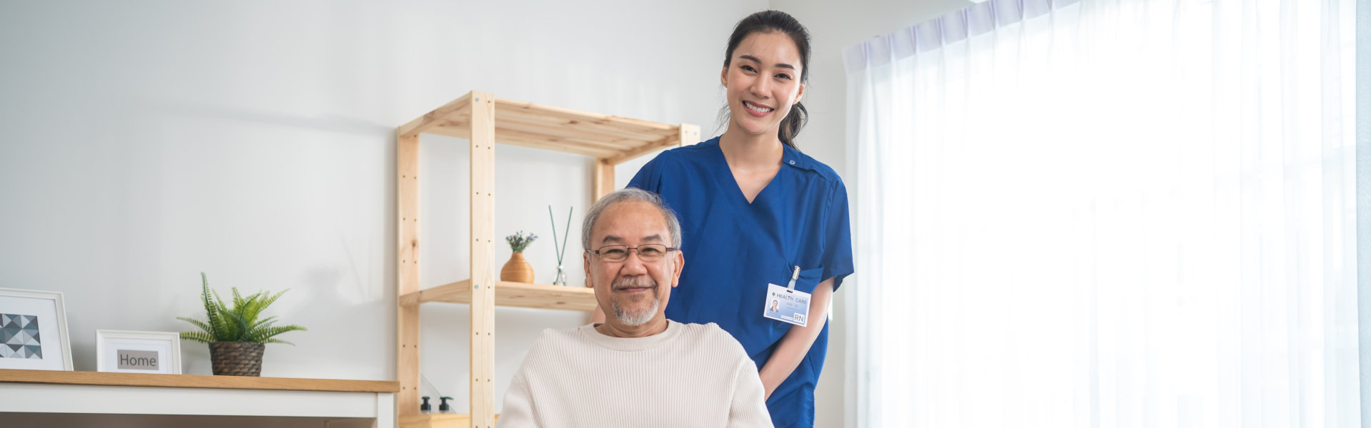 senior man on wheelchair and caregiver posing and smiling together